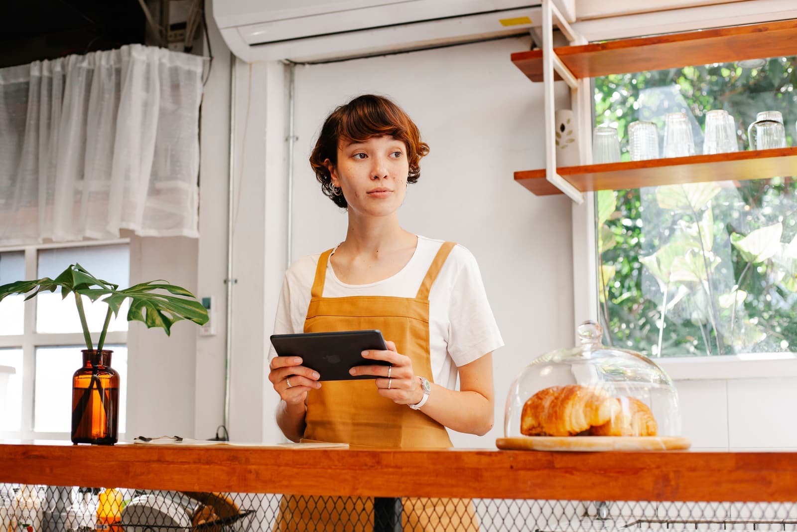 Une commerçante consulte une tablette derrière son comptoir.