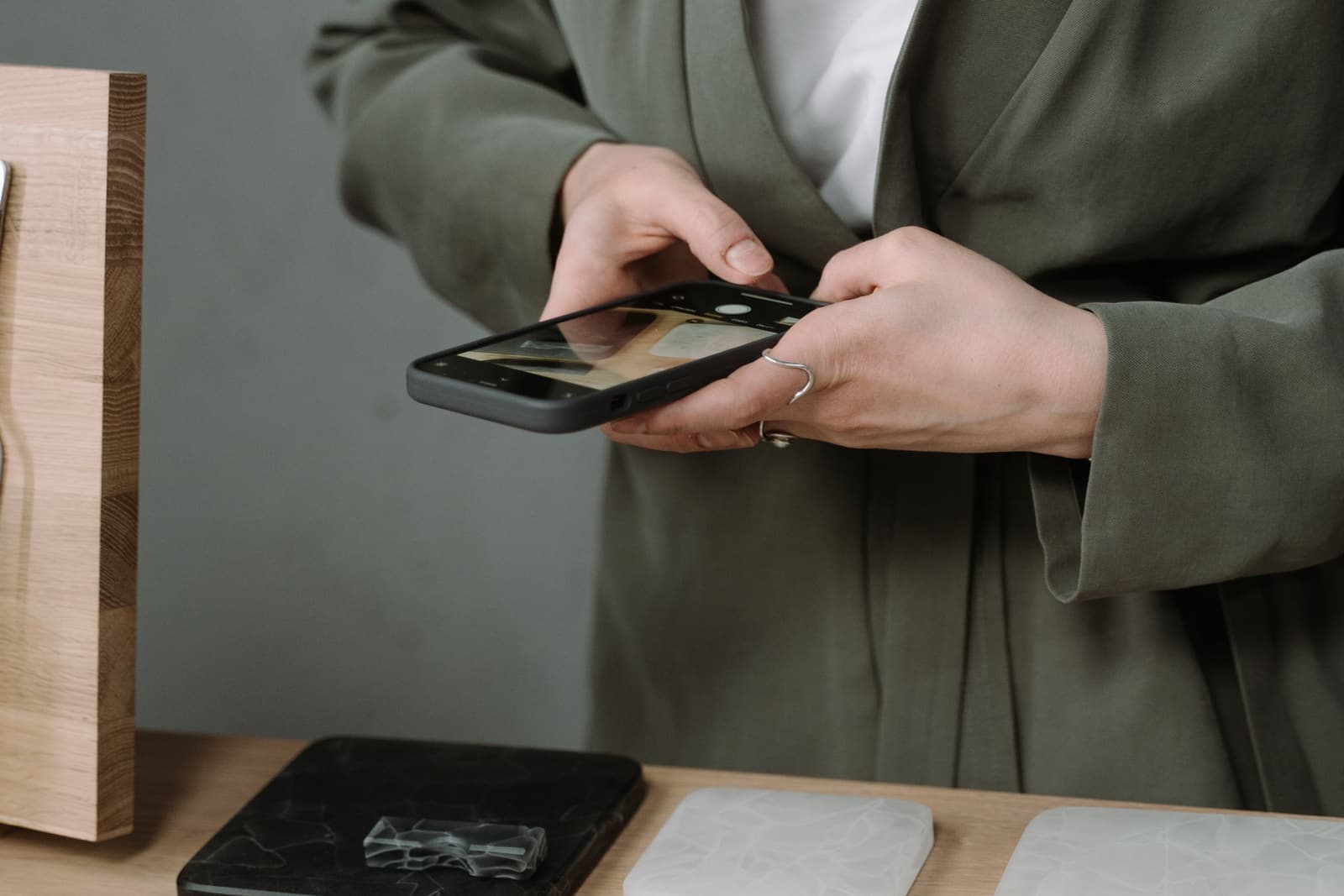 Mains photographiant des objets artisanaux sur une table avec un téléphone.